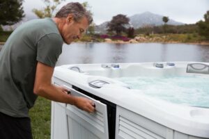 man opening his hot tub access panel to perform hot tub maintenance